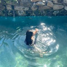 a woman swimming in the water with her hand up