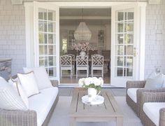 an outdoor living room with wicker furniture and glass doors leading to the dining area