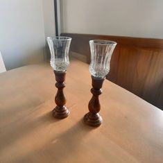 two clear glass vases sitting on top of a wooden table next to each other