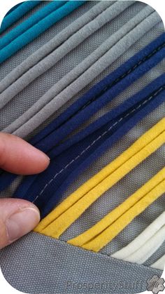 a person is holding onto some blue, yellow and grey material with their fingers on it