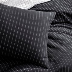 black and white pinstripe bedding with two pillows on top of each other