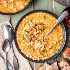 two bowls filled with beans and bread on top of a table