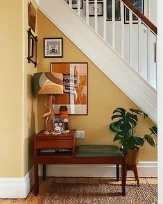 an entryway with a bench, lamp and pictures on the wall next to it