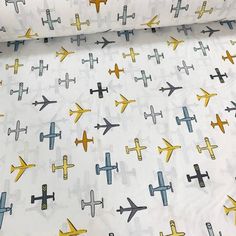 an airplane print on white fabric with yellow and blue planes all over it, as well as the background