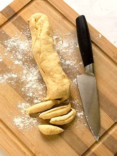 a wooden cutting board topped with dough next to a knife