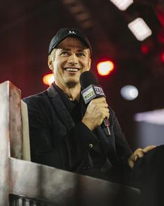 a man holding a microphone and smiling at the camera