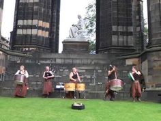 a group of people that are standing in the grass with some drums and drum sticks