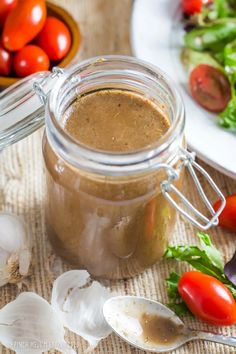 a glass jar filled with brown sauce next to some vegetables