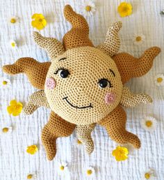 a crocheted sunflower laying on top of a white sheet with daisies