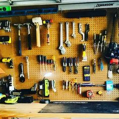 a workbench with lots of tools hanging on the wall