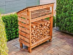 a stack of logs sitting on top of a wooden stand next to some shrubbery