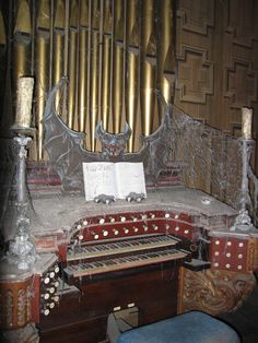 an old pipe organ in the corner of a room with candles and music sheets on it