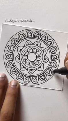 someone is drawing a flower in the middle of a piece of paper with a marker