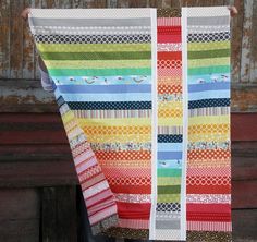 a woman is holding up a colorful quilt