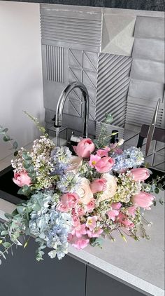 a bouquet of flowers sitting on top of a kitchen counter next to a faucet