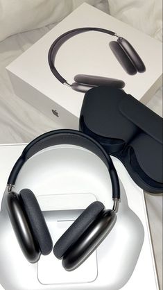 two black headphones sitting on top of a white box next to a pair of glasses