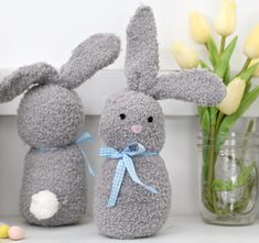 two stuffed animals sitting next to each other on a shelf with tulips in the background