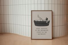 a bathroom with a bathtub on the floor and a framed poster above it that says, what happens in the bathtub stays in the bathroom