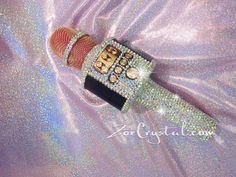 a close up of a cell phone on a shiny surface with lots of beads and sequins