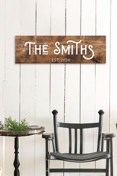 a wooden sign that says the smiths on it next to a chair and table