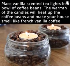 two glass jars filled with coffee beans on top of a wooden table next to a lit candle