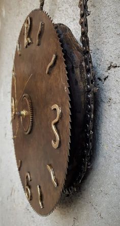 an old clock hanging on the wall with chains around it's edges and numbers