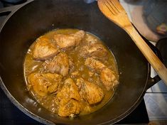 chicken and gravy in a skillet with a wooden spoon on the stove