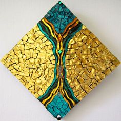 a gold and blue square shaped artwork on a white wall