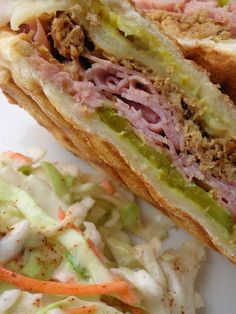 a sandwich cut in half sitting on top of a plate next to coleslaw