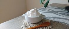 a wooden spoon sitting on top of a table next to a cup filled with whipped cream