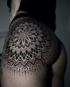 the back of a woman's lower body with an intricate tattoo design on it