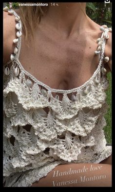 a woman wearing a white crocheted top with pearls