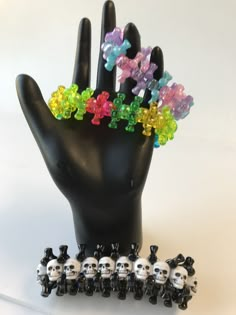 a hand with several skulls and flowers on it, next to a beaded bracelet