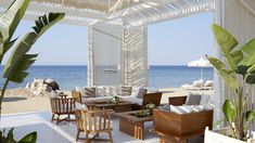 an outdoor seating area with chairs, tables and umbrellas on the beach next to the ocean