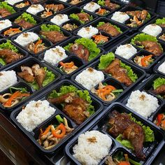 many trays of food with meat, rice and vegetables in them on a table