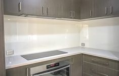 an empty kitchen with stainless steel appliances and white counter tops, including a dishwasher