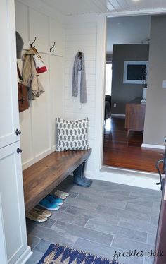 a wooden bench sitting in the middle of a living room next to a wall mounted coat rack