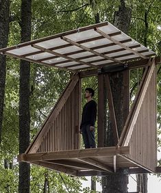 a man standing on top of a wooden tree house