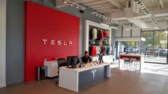 the inside of a tesla store with people sitting at desks in front of it