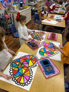 children are sitting at desks in a classroom with stained glass designs on the table