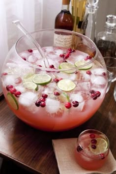 a pitcher filled with ice and cranberries on top of a table next to glasses