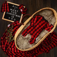 a red and black plaid baby's outfit in a basket with a sign that says all i want for christmas is you