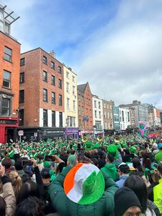 a large group of people with irish flags on their heads in the middle of a street