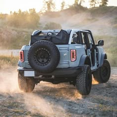 a gray truck driving down a dirt road