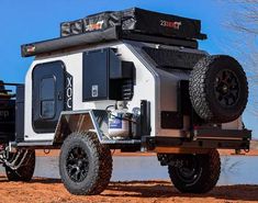 an off road camper parked on the side of a dirt road next to a body of water