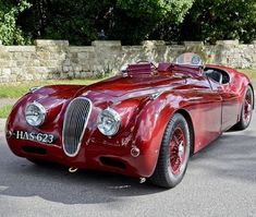 an old red sports car is parked on the street