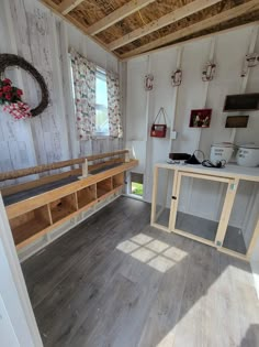 the inside of a tiny house with wood floors and white walls, windows, and wooden shelves