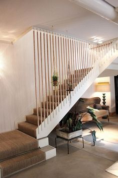 a living room filled with furniture and a stair case next to a plant on top of a table