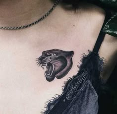 a woman's chest with a black and grey tattoo design on it, featuring an angry cat