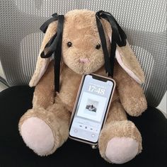 a stuffed animal sitting on top of a chair next to an mp3 player in its lap